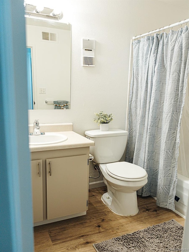 bathroom featuring toilet, visible vents, vanity, shower / bathtub combination with curtain, and wood finished floors