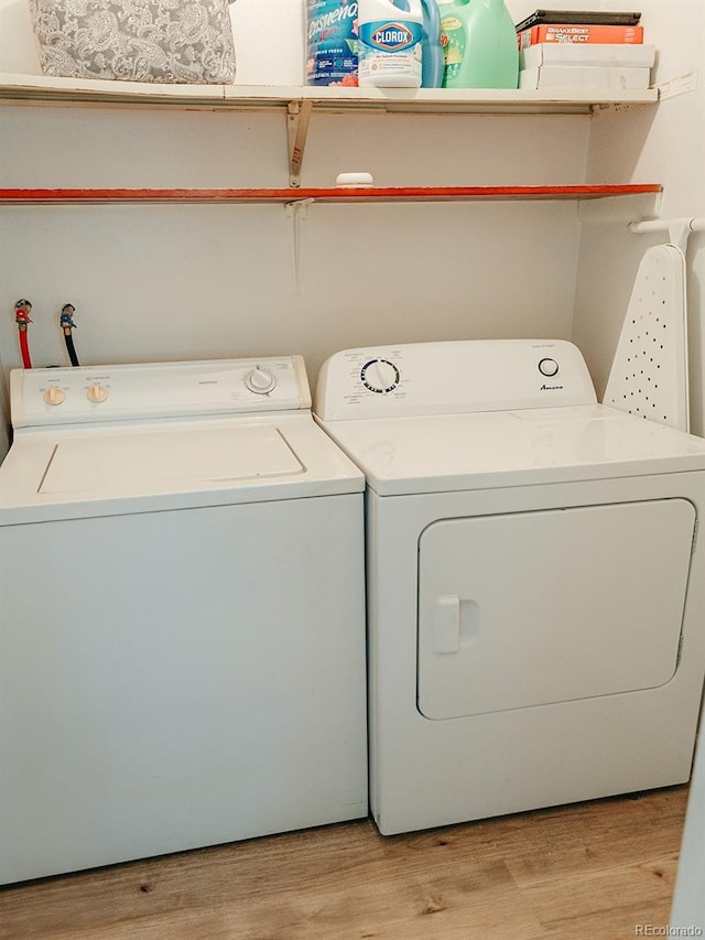 clothes washing area featuring washing machine and clothes dryer, laundry area, and light wood-style flooring