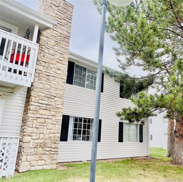 view of home's exterior featuring a chimney and a balcony