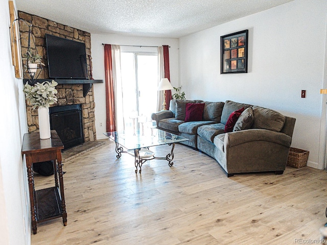 living room with light wood finished floors, a textured ceiling, and a fireplace