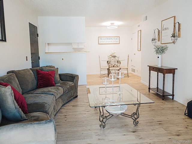 living room with baseboards, visible vents, and wood finished floors