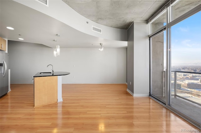 kitchen with expansive windows, stainless steel refrigerator with ice dispenser, light hardwood / wood-style flooring, and decorative light fixtures