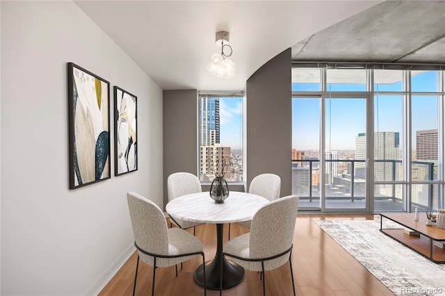 dining room featuring hardwood / wood-style flooring, floor to ceiling windows, and a notable chandelier