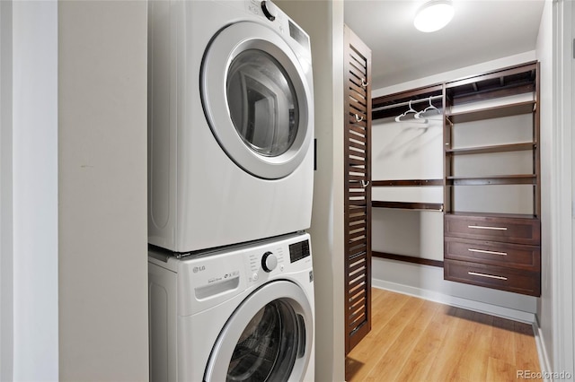 clothes washing area with stacked washer / drying machine and light hardwood / wood-style flooring