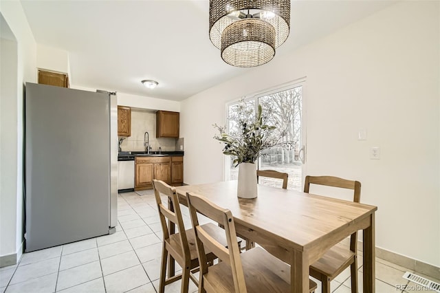 dining room featuring sink, light tile patterned floors, and an inviting chandelier