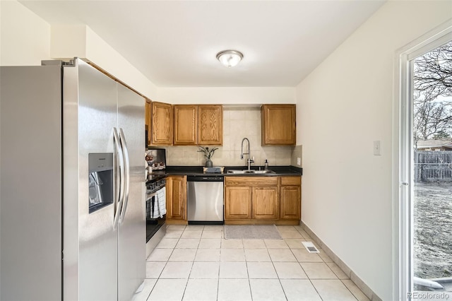 kitchen featuring sink, backsplash, light tile patterned floors, and appliances with stainless steel finishes