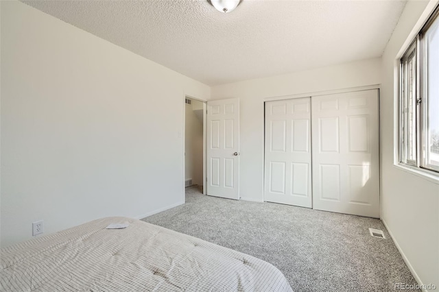 unfurnished bedroom with carpet floors, a textured ceiling, and a closet