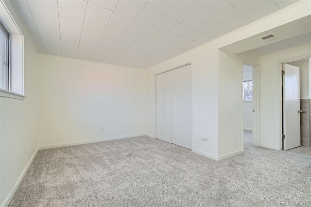 unfurnished bedroom featuring a closet and light carpet