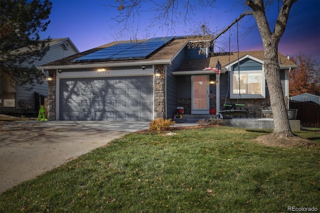 view of front of home featuring a yard, a garage, and solar panels