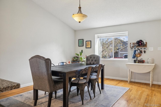 dining area featuring vaulted ceiling and light hardwood / wood-style flooring