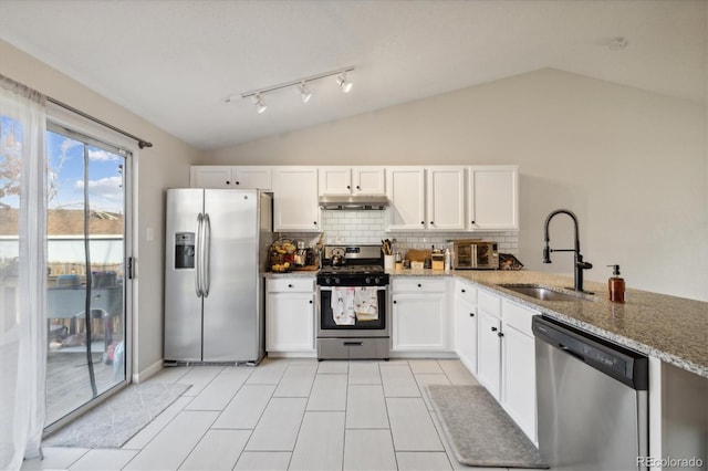 kitchen featuring lofted ceiling, sink, appliances with stainless steel finishes, light stone counters, and white cabinetry