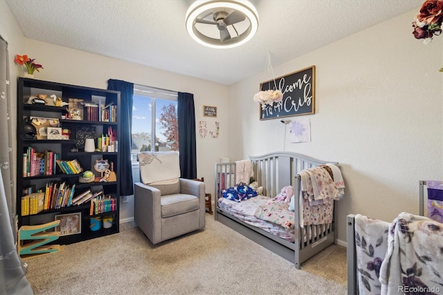 carpeted bedroom featuring a crib and a textured ceiling