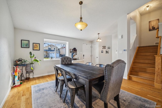 dining space with baseboards, a textured ceiling, stairway, and wood finished floors