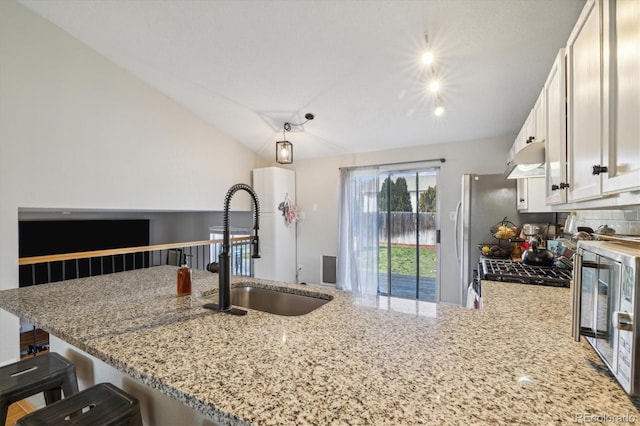 kitchen featuring a peninsula, exhaust hood, a sink, backsplash, and light stone countertops