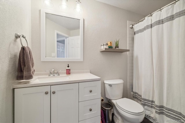 bathroom featuring a textured wall, vanity, toilet, and a shower with curtain