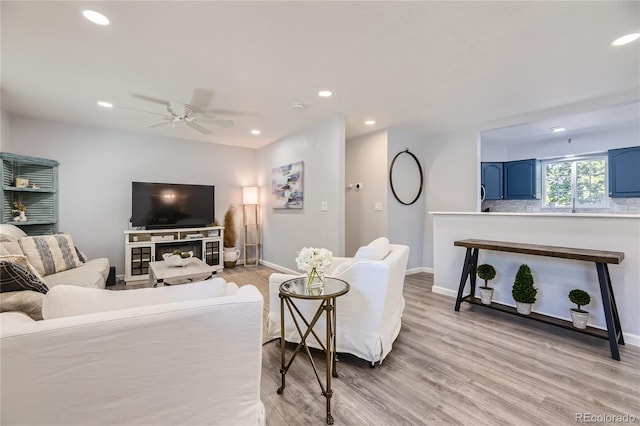 living room featuring light hardwood / wood-style flooring and ceiling fan