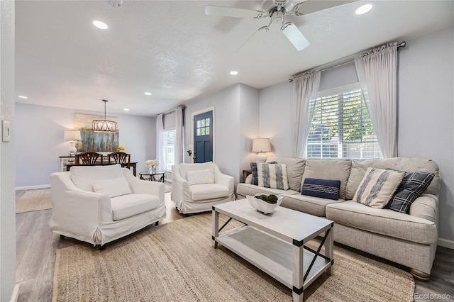 living room with ceiling fan with notable chandelier and light wood-type flooring