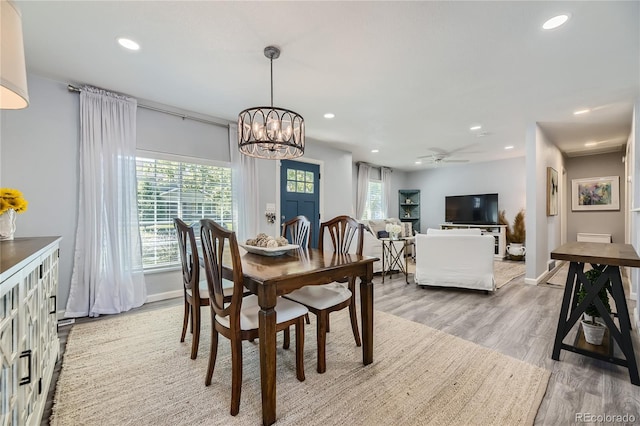 dining space with hardwood / wood-style floors, ceiling fan with notable chandelier, and plenty of natural light