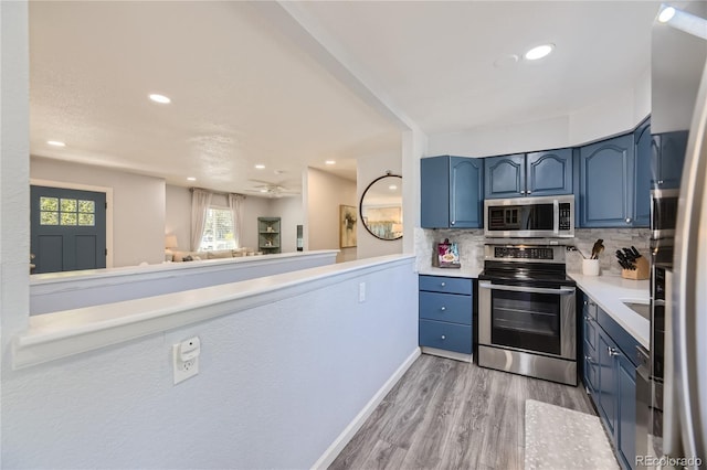 kitchen featuring backsplash, blue cabinetry, stainless steel appliances, and light wood-type flooring