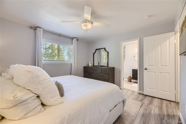 bedroom featuring light wood-type flooring, ensuite bath, and ceiling fan