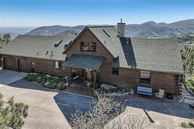 10450 Hondah Dr, Littleton, CO 80127 - view of property exterior with log exterior, a mountain view, a shingled roof, a chimney, and concrete driveway