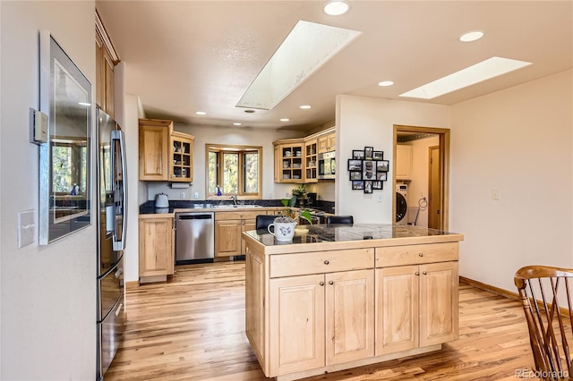 10450 Hondah Dr, Littleton, CO 80127 - kitchen with appliances with stainless steel finishes, a skylight, light brown cabinetry, washer / clothes dryer, and recessed lighting