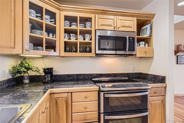 10450 Hondah Dr, Littleton, CO 80127 - kitchen with stainless steel appliances, light brown cabinetry, tile countertops, glass insert cabinets, and wood finished floors