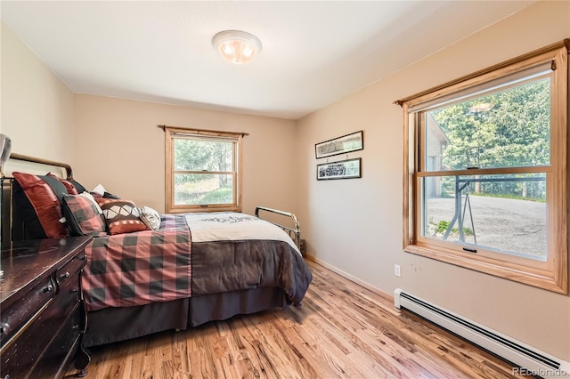10450 Hondah Dr, Littleton, CO 80127 - bedroom featuring a baseboard heating unit, light wood-style floors, and baseboards