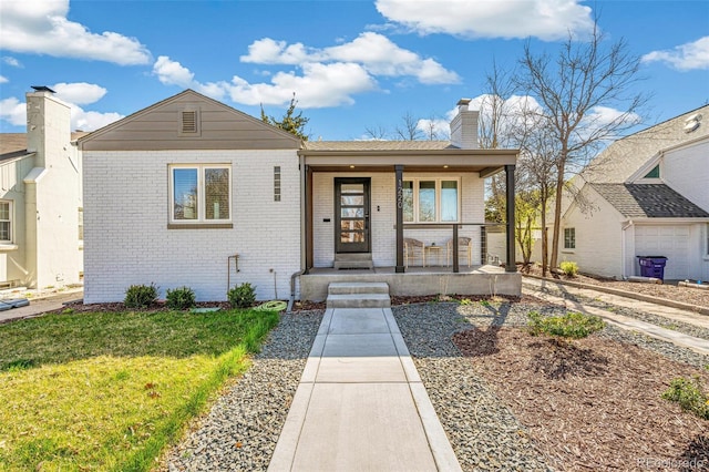 1220 Ash St, Denver, CO 80220 - bungalow featuring a chimney, a front lawn, brick siding, and covered porch