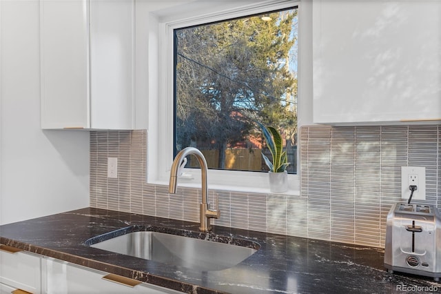 1220 Ash St, Denver, CO 80220 - interior details featuring a sink, decorative backsplash, dark stone countertops, and white cabinets