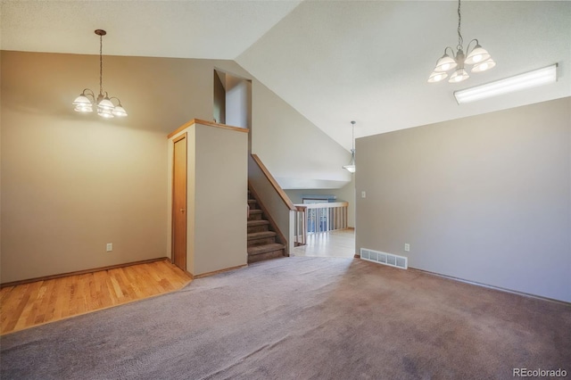 unfurnished living room with carpet flooring, a notable chandelier, and high vaulted ceiling