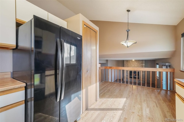 kitchen with black fridge, decorative light fixtures, light hardwood / wood-style flooring, and white cabinets