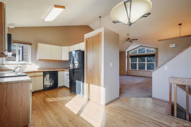 kitchen with lofted ceiling, sink, hanging light fixtures, light hardwood / wood-style floors, and black appliances