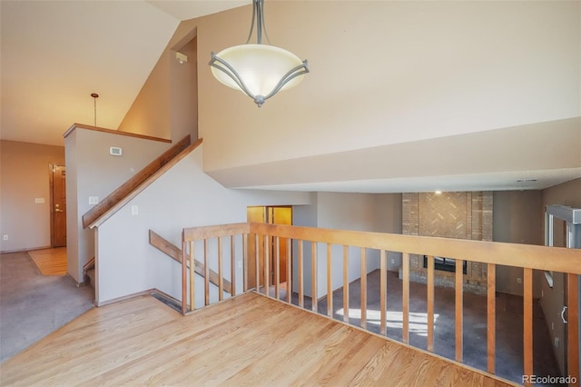 stairs featuring wood-type flooring and high vaulted ceiling