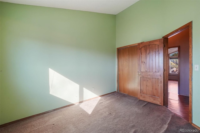 unfurnished bedroom with a towering ceiling and dark colored carpet