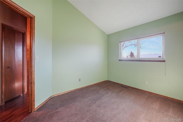 carpeted empty room featuring vaulted ceiling