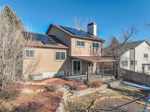 back of house with central AC and solar panels