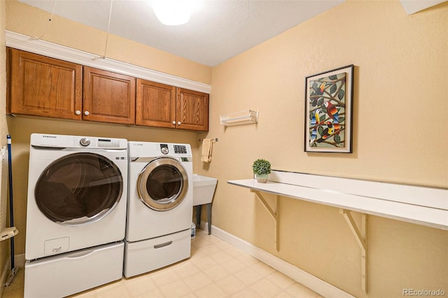laundry area featuring separate washer and dryer, cabinet space, and baseboards
