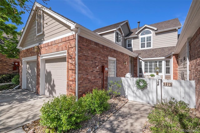 view of property exterior featuring brick siding, fence, driveway, and a shingled roof