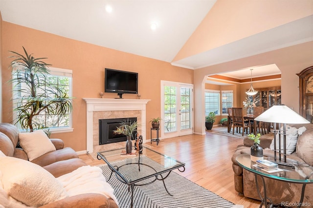 living area with arched walkways, a fireplace, plenty of natural light, wood finished floors, and recessed lighting