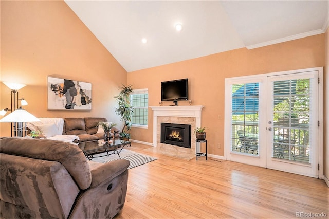 living room with light wood-style flooring, a fireplace, high vaulted ceiling, baseboards, and crown molding