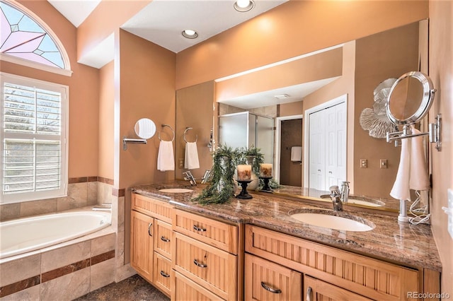 bathroom with double vanity, a stall shower, and a garden tub