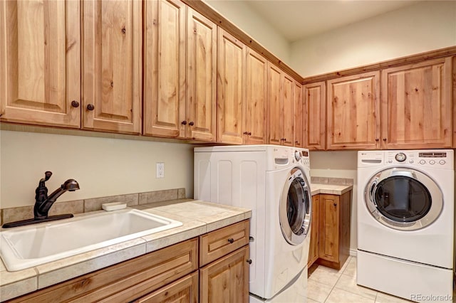 clothes washing area with washing machine and dryer, cabinet space, a sink, and light tile patterned flooring