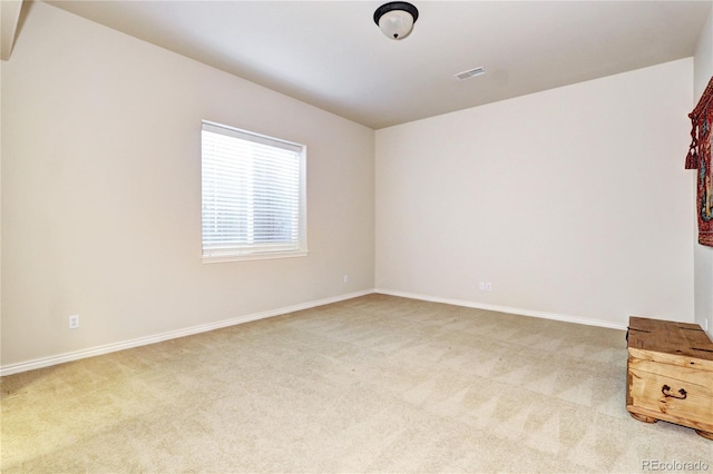 spare room featuring baseboards, visible vents, and light colored carpet