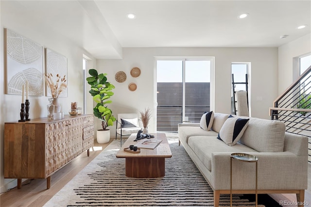 living area with a healthy amount of sunlight, stairway, wood finished floors, and recessed lighting