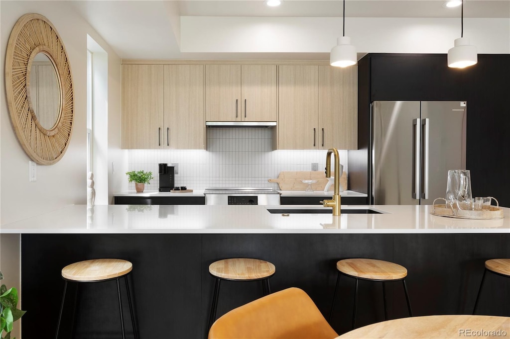 kitchen featuring light countertops, decorative backsplash, a sink, freestanding refrigerator, and modern cabinets