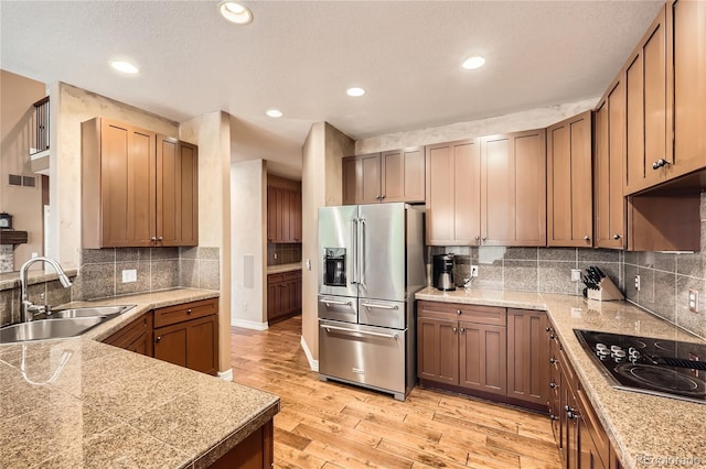 527 Stonemont Dr, Castle Pines, CO 80108 - kitchen featuring stainless steel fridge with ice dispenser, a sink, black electric stovetop, tile countertops, and light wood-style flooring
