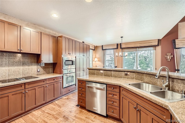 527 Stonemont Dr, Castle Pines, CO 80108 - kitchen with appliances with stainless steel finishes, a sink, backsplash, light wood-type flooring, and pendant lighting