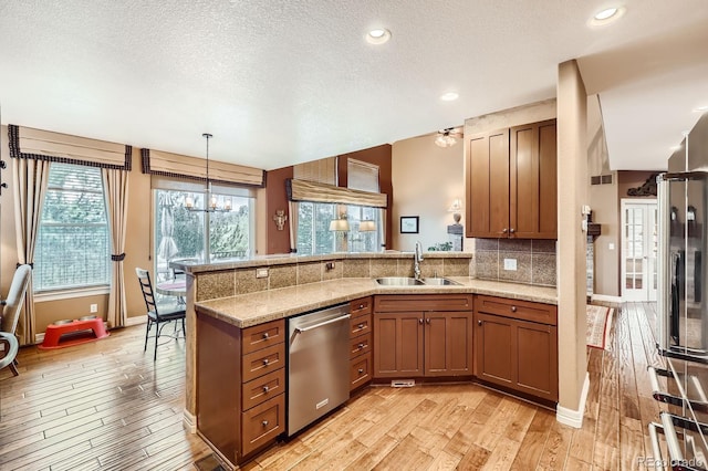 527 Stonemont Dr, Castle Pines, CO 80108 - kitchen with dishwasher, a sink, a peninsula, light wood-style flooring, and a textured ceiling