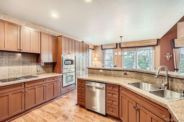 527 Stonemont Dr, Castle Pines, CO 80108 - kitchen featuring stainless steel appliances, a sink, decorative backsplash, light wood finished floors, and pendant lighting